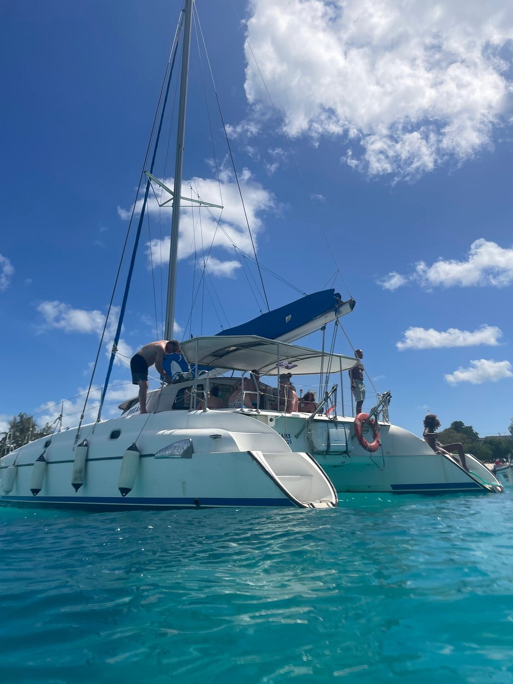 Dreams at anchor in clear turquoise water off the west coast of Barbados, guests on deck and a swimmer coming down the sugar-scoop